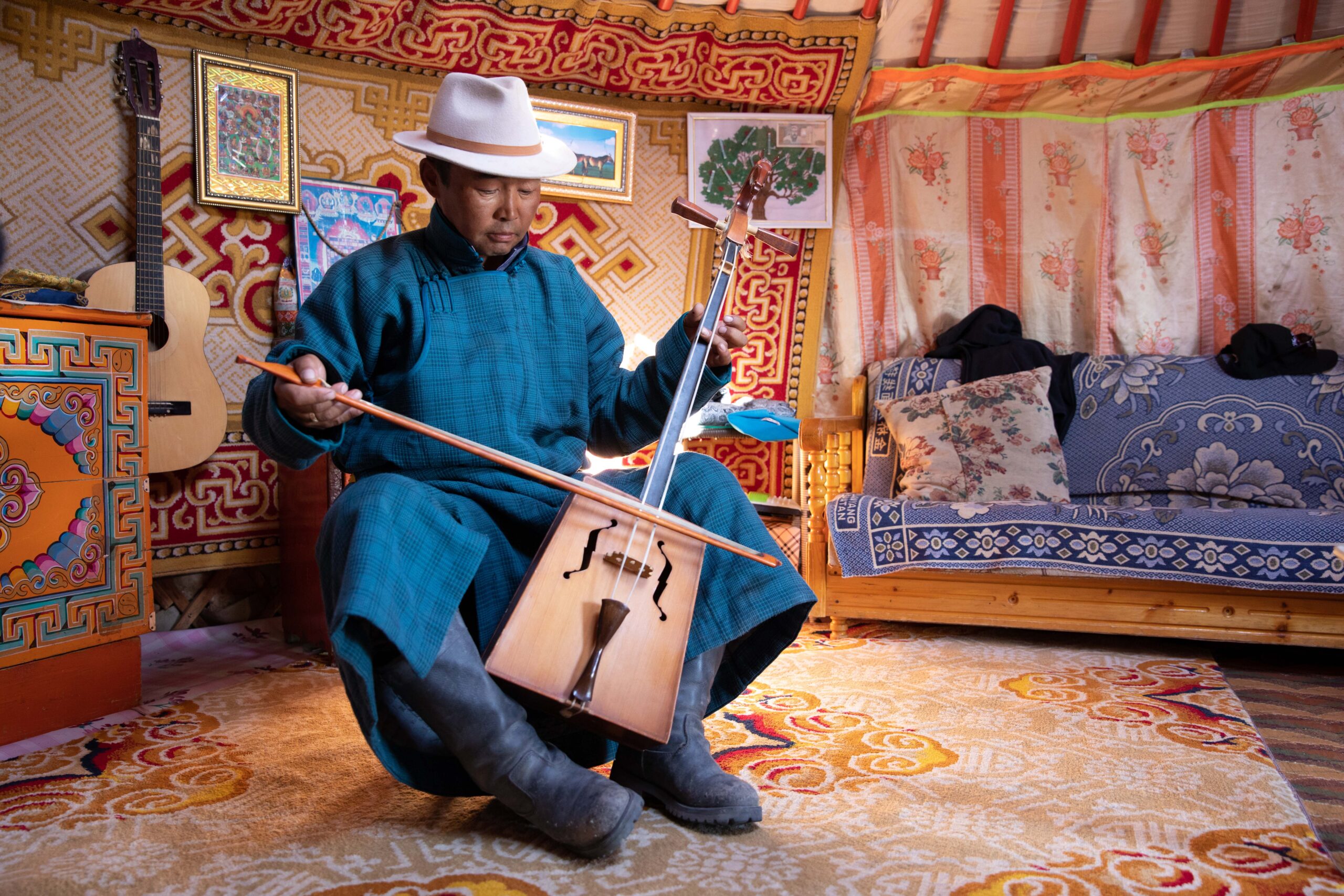 Gobi desert, Mongolia. Sep 17, 2019: Nomadic man in traditional deel playing the horse-headed fiddle in his ger home.