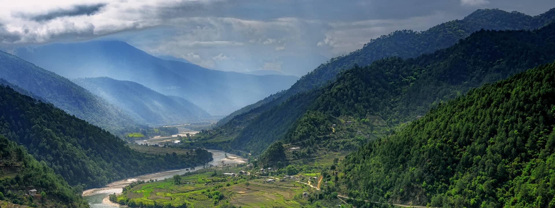 Valley in Bhutan near Punakha with rice fields and typical houses. Travel to Bhutan and enjoy the beautiful landscape of farms and mountains in this buddhist country.